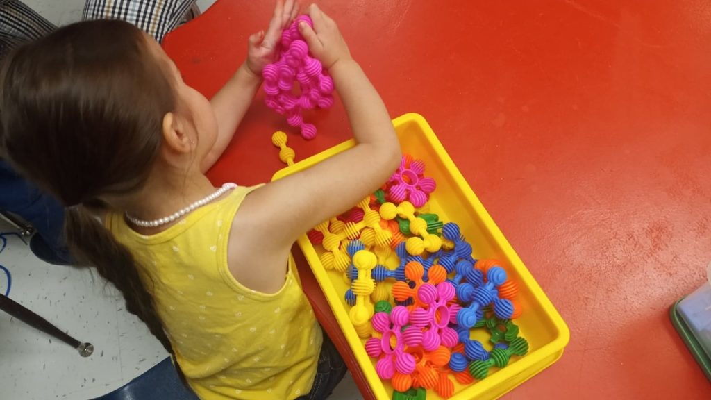 A child participating in play-based learning by playing with a small tub of building pieces